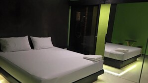 A modern bedroom with a large bed, a mirror, and a small table. - i DUS Resort (Phitsanulok)
