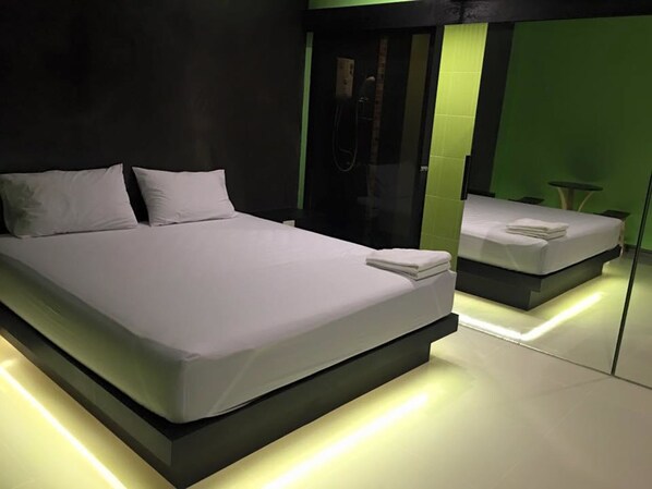 Quarto moderno com uma cama grande, um espelho e uma mesinha.