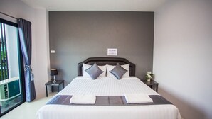 A hotel room with a large bed, a nightstand, a lamp, and a window with curtains. - The Bed Hotel (Phitsanulok)