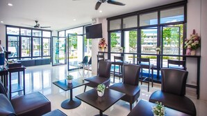 A modern hotel lobby with a seating area, large windows, and ceiling fans. - The Bed Hotel (Phitsanulok)