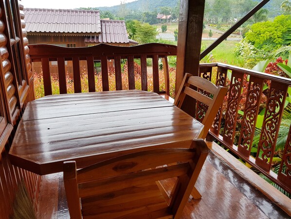 A wooden bench with a view of a house and lush greenery. - Khao Kho Lucky Hill Resort (Khao Kho)