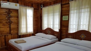 Habitación de madera con dos camas, ropa de cama blanca y un aire acondicionado colgante.