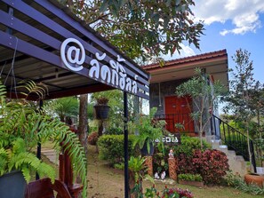 A hotel entrance with a sign, a staircase, and a garden with various plants. - Khao Kho Lucky Hill Resort (Khao Kho)