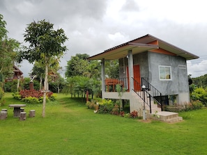 A two-story house with a balcony, surrounded by lush greenery and a well-maintained lawn. - Khao Kho Lucky Hill Resort (Khao Kho)