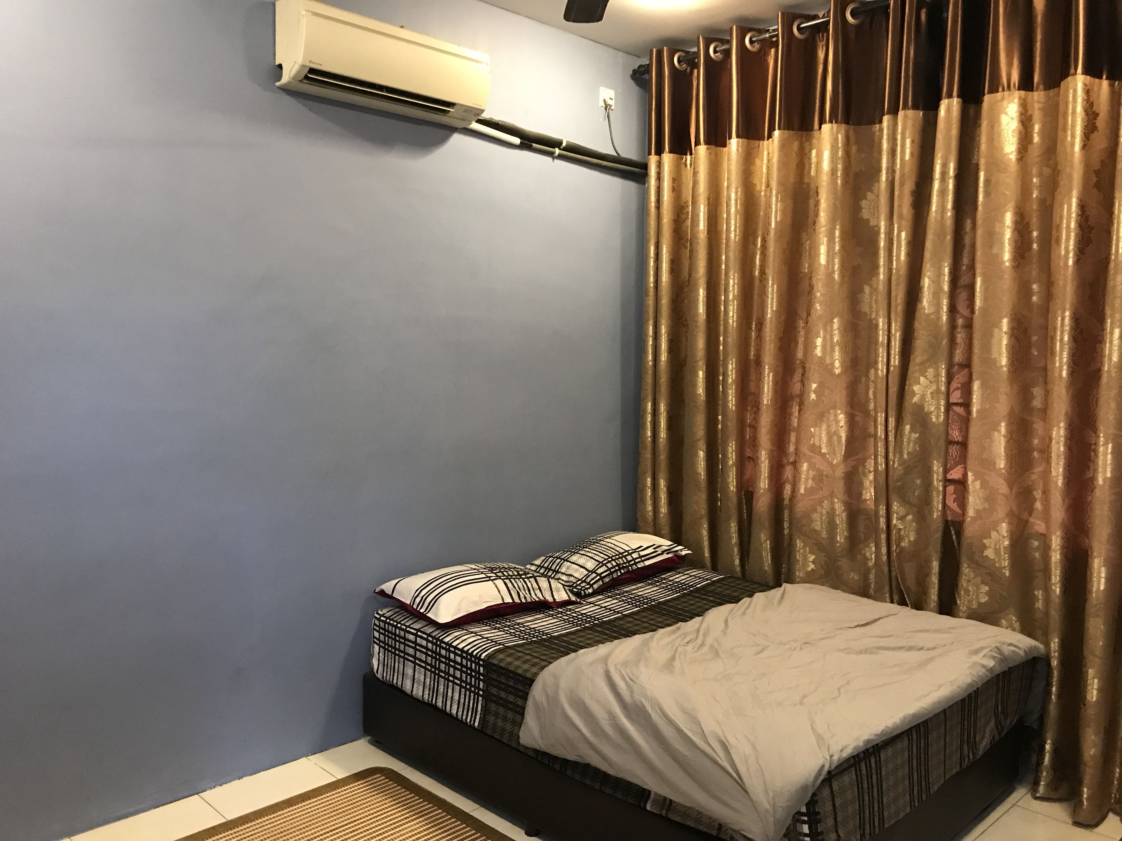 A bedroom with a bed, a wall-mounted air conditioner, and a curtain.