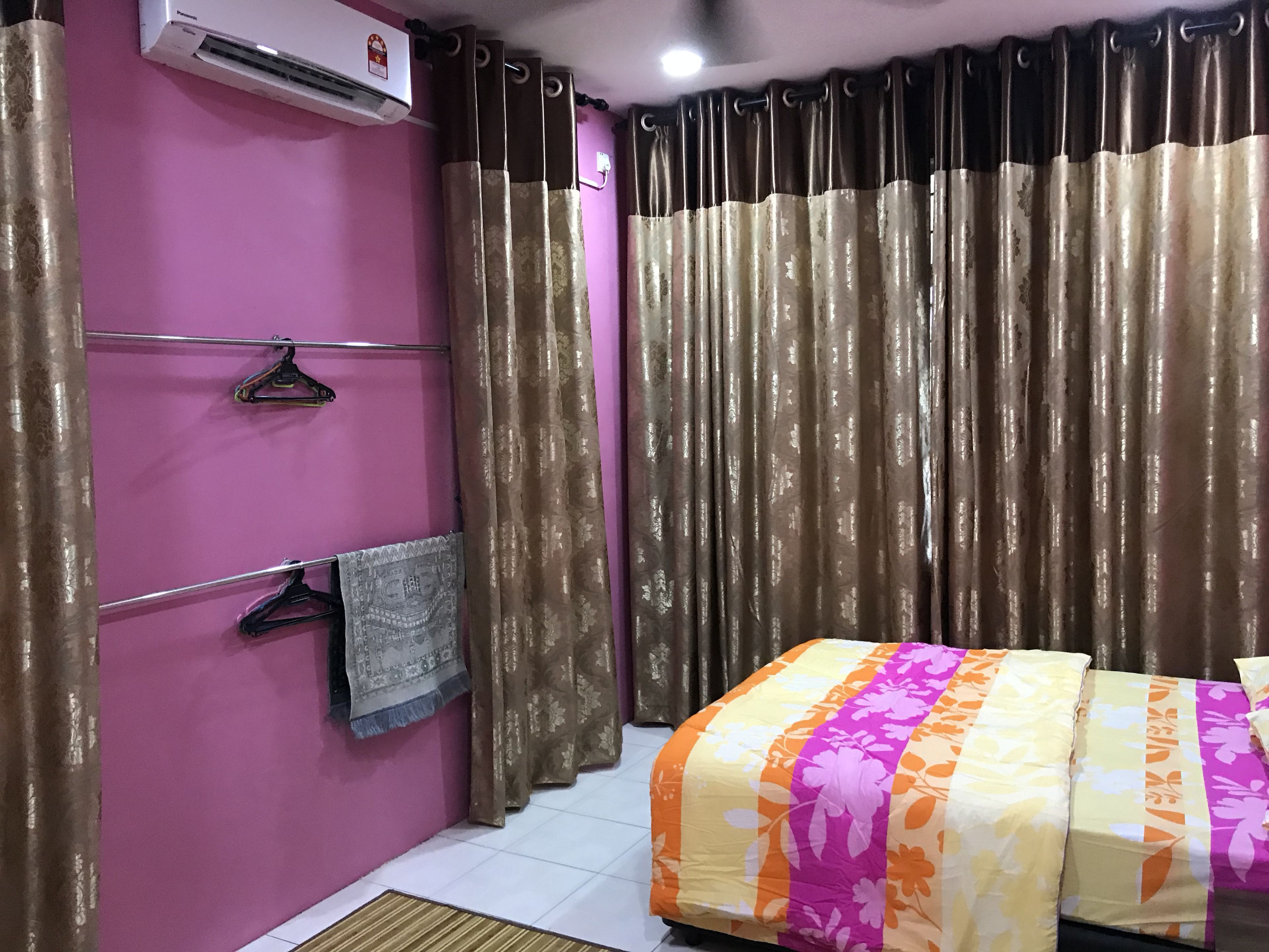 Une chambre à coucher avec un lit, une serviette suspendue, un climatiseur fixé au mur et un rideau.