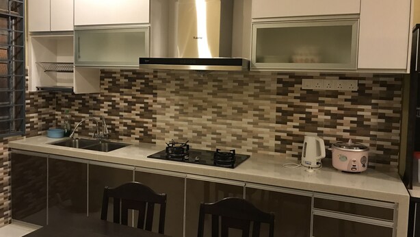 A modern kitchen with a tiled backsplash, stainless steel appliances, and a dining area with two chairs. - Aushaf Homestay Changlun (Changlun)