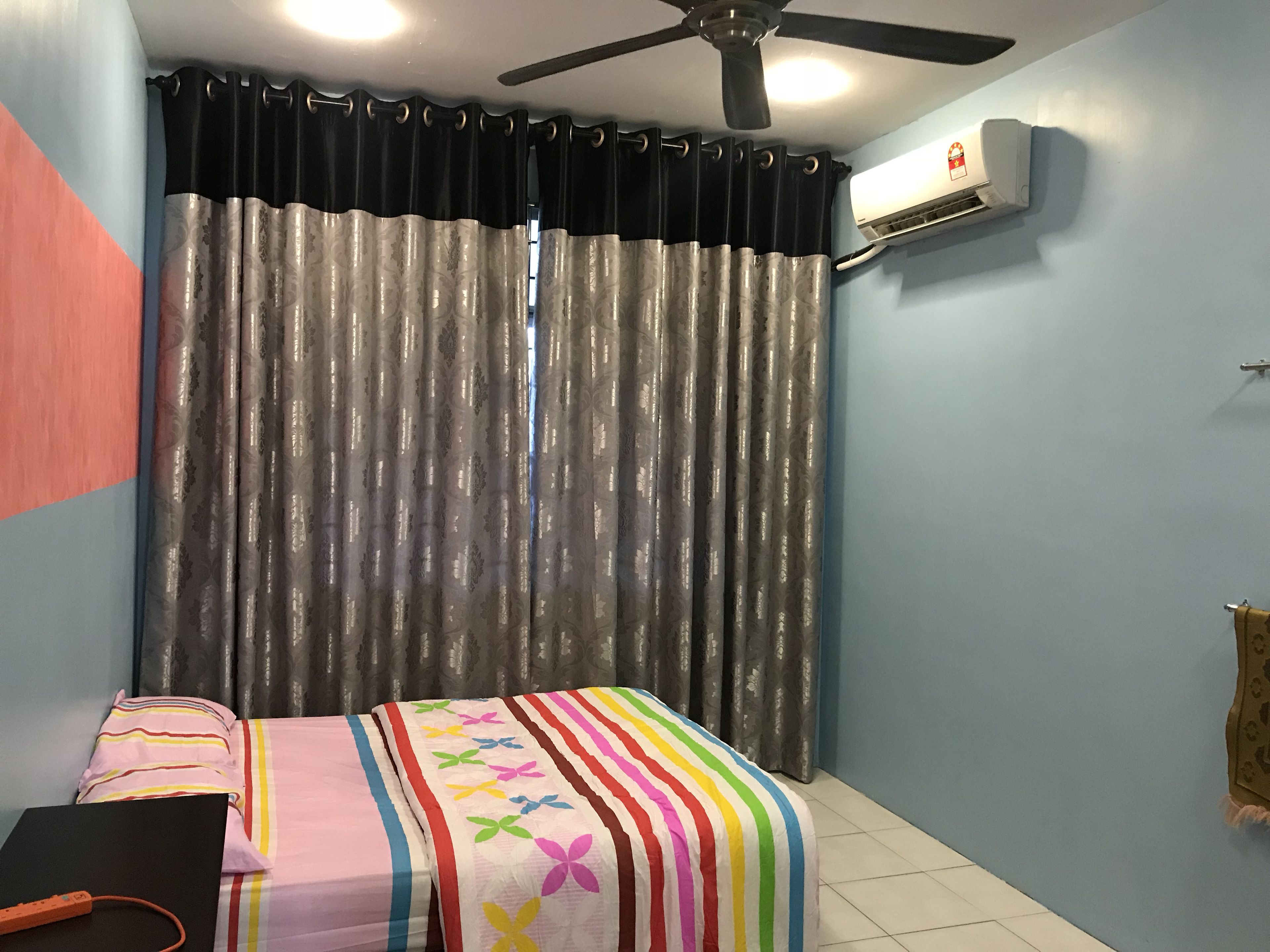 A bedroom with a bed, a ceiling fan, an air conditioning unit, and a curtain.