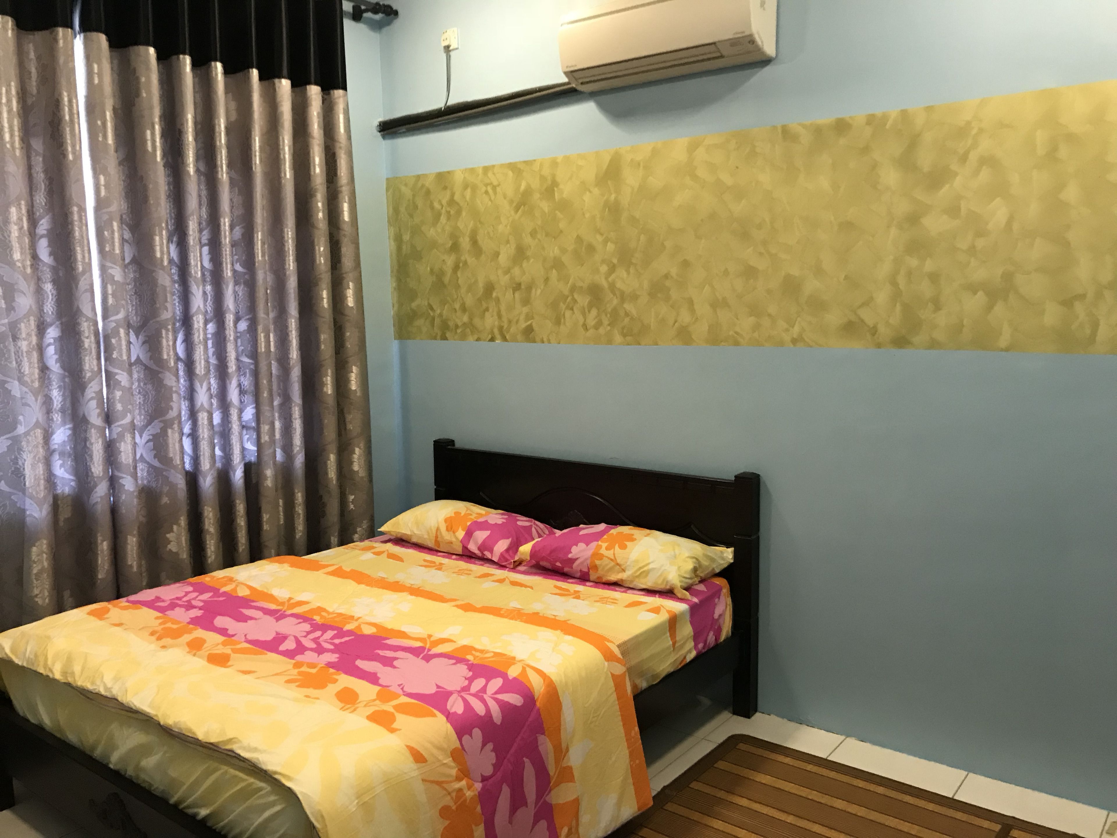 A bedroom with a bed, curtains, an air conditioning unit, and a textured wall.