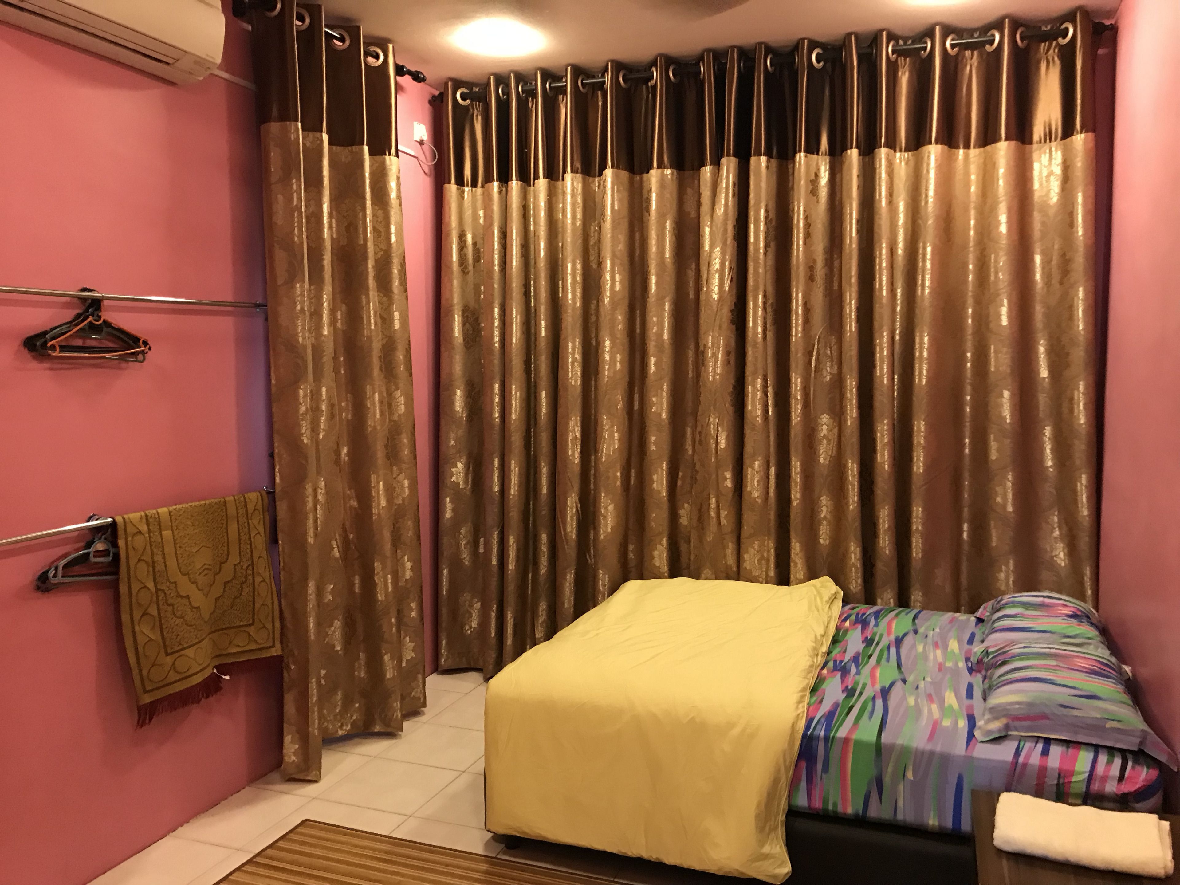 A bedroom with a bed, a bedside table, a hanging towel, and a curtain.