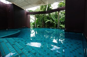 Piscina com revestimento de azulejos e vista para vegetação exuberante.