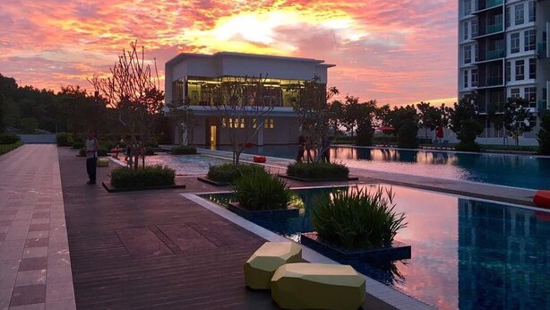 Un hotel moderno con zona de piscina, vistas al atardecer y un jardín bien cuidado.
