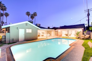 Une maison moderne dotée d’une piscine, d’un espace salon extérieur et de palmiers.