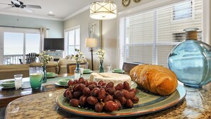 A dining area with a table set for a meal, including grapes and a loaf of bread.
