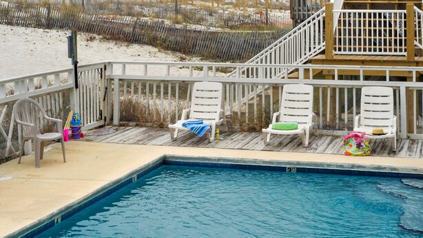 A pool area with white deck chairs and a wooden deck.