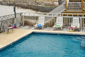 Ein Poolbereich mit weißen Liegestühlen und einer Holzterrasse.