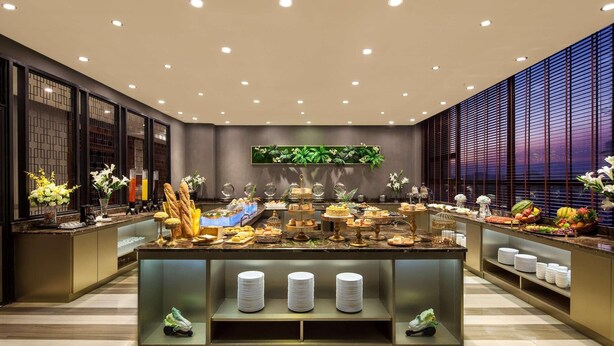 A buffet area with various food items and a display of plates. - Ramada by Wyndham Liuzhou Luzhai (Suzhou)