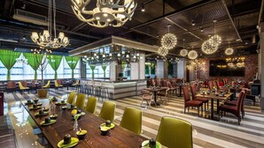 A spacious dining area with long tables, green chairs, and modern chandeliers. - Ramada by Wyndham Liuzhou Luzhai (Suzhou)
