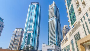 A high-rise building with a modern architectural design, featuring a prominent vertical structure and reflective glass facade. - DHH - Botanica Tower (Dubai)