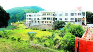 A multi-story building with a reception area, surrounded by lush greenery and a small pool.