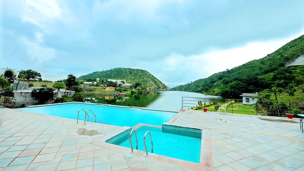 A swimming pool with a view of a lake and hills.