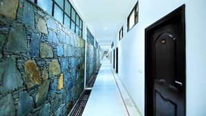 A hallway with a stone wall, a black door, and a number 208 on the door.