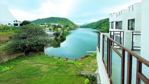 A riverside view with a building featuring a balcony overlooking the water.