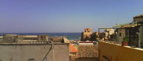 A rooftop with a view of the sea, featuring buildings with traditional architecture and a clear sky.