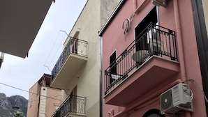 Un immeuble de deux étages doté de balcons, une entrée centrale avec une porte et un appareil de climatisation fixé à la façade.