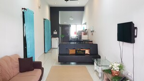 A modern living room with a sofa, a coffee table, and a TV mounted on the wall. - Fahaz Taiping Homestay (Taiping)