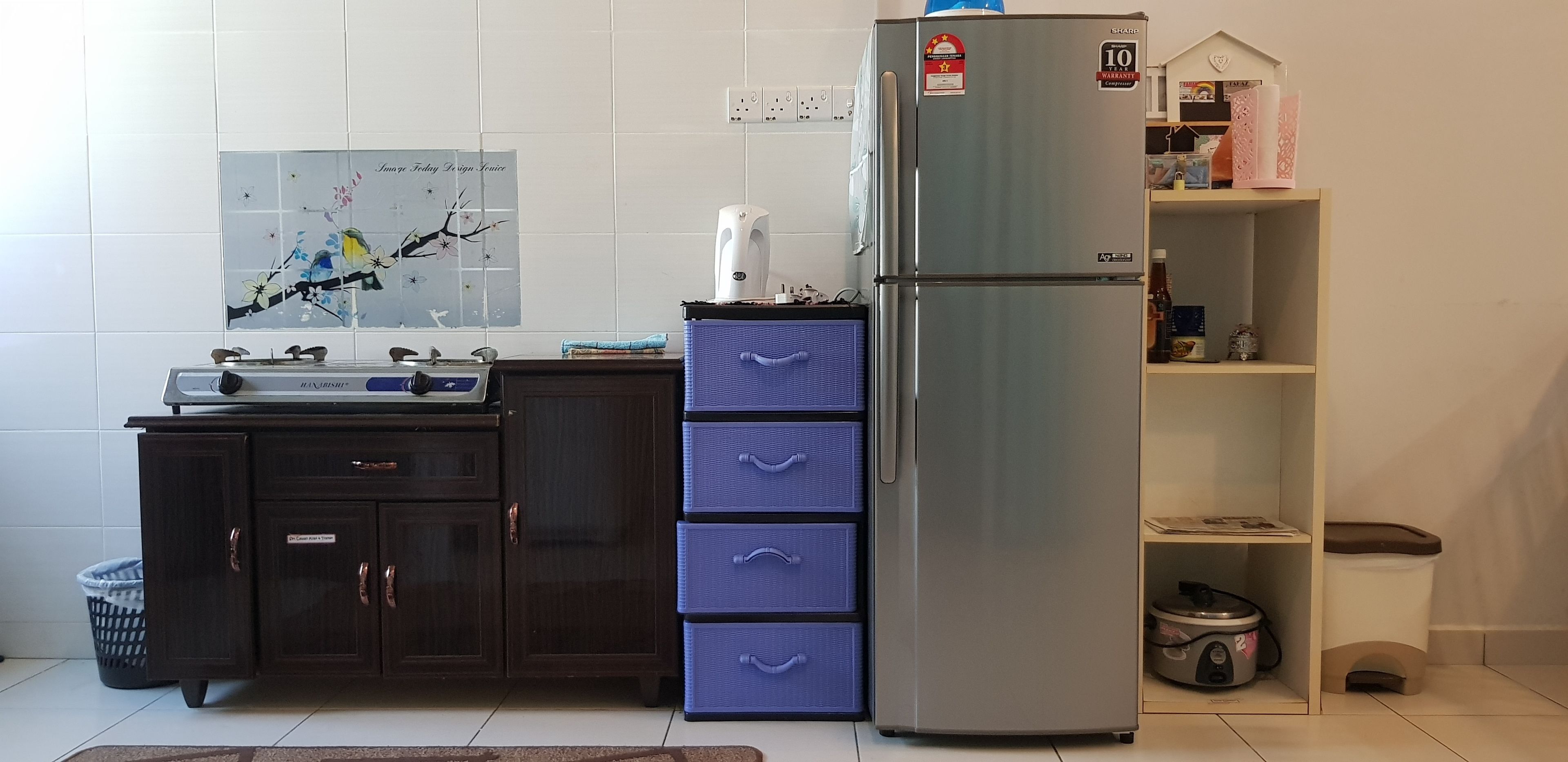 A kitchen with a stainless steel refrigerator, a microwave, a sink, and a blue storage unit.