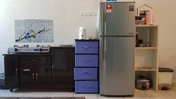 A kitchen with a stainless steel refrigerator, a microwave, a sink, and a blue storage unit.