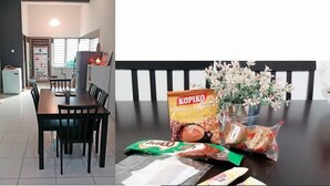 A dining area with a wooden table, chairs, a vase with flowers, and food packages. - Fahaz Taiping Homestay (Taiping)