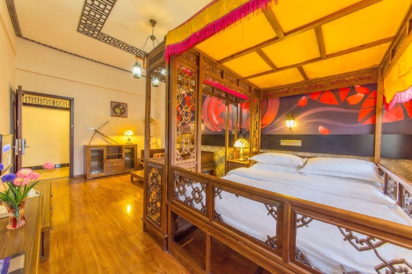 Una habitación tradicional con una cama con dosel, muebles de madera y un mural decorativo en la pared.