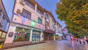 A building with multiple storefronts, including a visible sign for a hand-painted shop. - The home of art and painting (Lijiang)