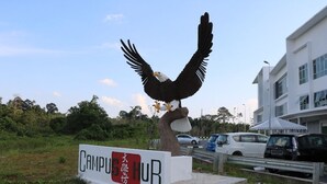 Letrero de centro universitario con una gran escultura de águila.