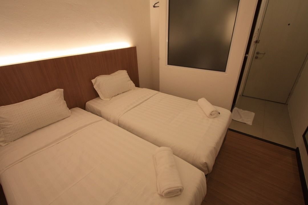 A hotel room with two beds, a wooden headboard, a large mirror, and a door.