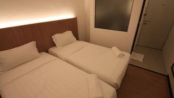 A hotel room with two beds, a wooden headboard, a large mirror, and a door.