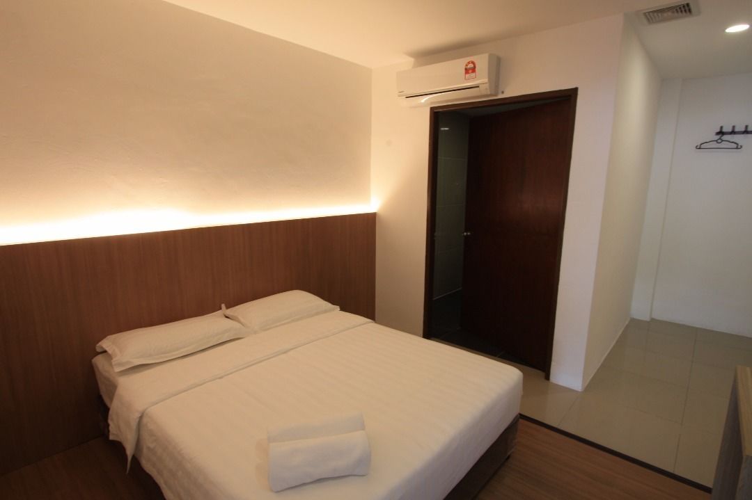 Habitación de hotel con una cama bien hecha, un cabecero de madera, aire acondicionado montado en la pared y una puerta que da a un armario.