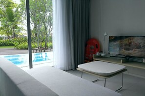 A modern room with a pool view, a massage table, and a TV.