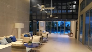 Un vestíbulo amplio con mobiliario moderno, ventanas grandes y ventiladores de techo.
