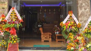 Exterior del encantador Charming Danang Hotel, con una entrada despejada, una silla de madera y decoración floral.