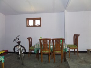 A room with a dining table and four chairs, a bicycle, and a window. - Agung Safira Homestay (Ngadisari)