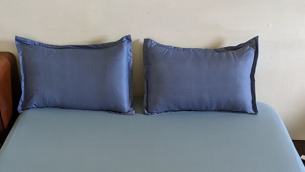A bed with a blue and white bedspread, two pillows, and a wooden headboard. - The Lodge for Cyclists - Hostel (Fangliao)