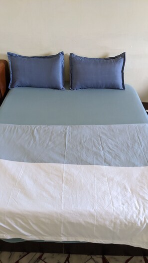 A bed with a blue and white bedspread, two pillows, and a wooden headboard. - The Lodge for Cyclists - Hostel (Fangliao)