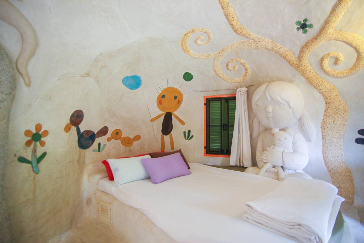 A bedroom with a bed, pillows, a window with curtains, and wall art.