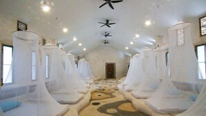 A room with four beds, each covered with white canopies, and a patterned floor. - Naidee Sculptured Huts (Hua Hin)