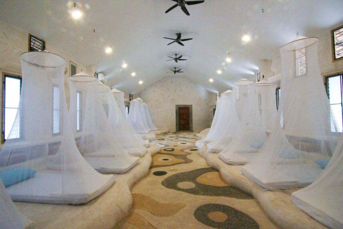 A room with four beds, each covered with white canopies, and a patterned floor.