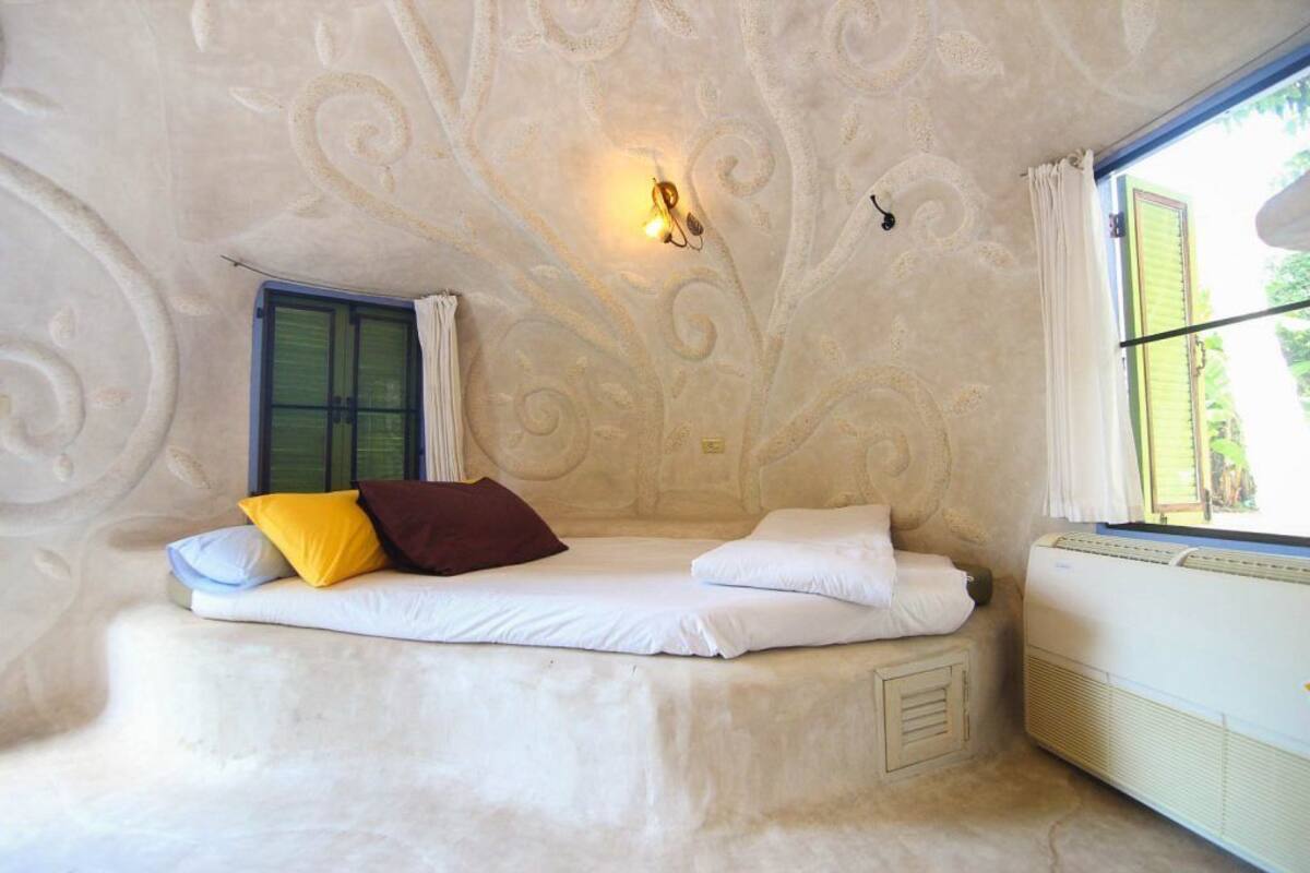 A cozy room with a bed, a window, and a wall with decorative patterns.