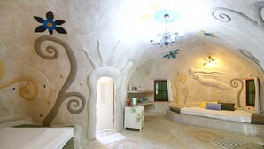 A room with a unique ceiling design, a bed, a small table, and a sofa. - Naidee Sculptured Huts (Hua Hin)